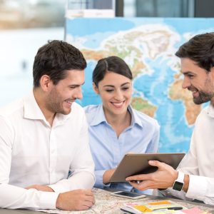 Young Man Travel Agent with Clients Concept Young man and couple sitting in office travel agency